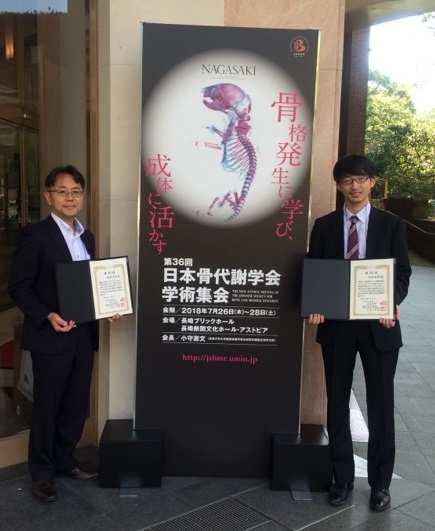 イメージ：学会会場の前で記念撮影　（優秀演題賞を受賞した医学系研究科大学院生の田中智哉さん（右）とダブル受賞！）